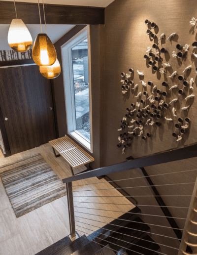 Modern home interior with artistic wall decor, pendant lights, and a staircase leading downstairs.